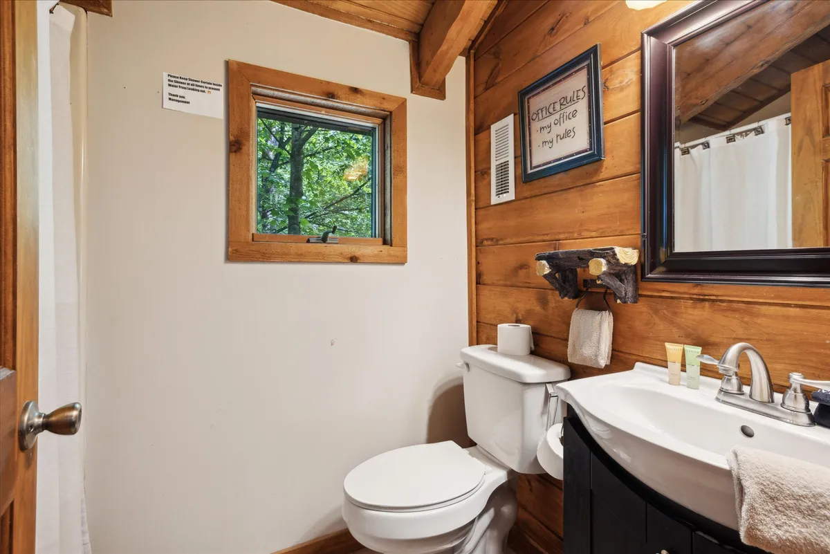 A cozy interior bathroom space, highlighted by wooden beams and a window that offers a view of the outdoors. The natural light streaming in and the tranquil feel of the room allow guests to connect with nature even while indoors.